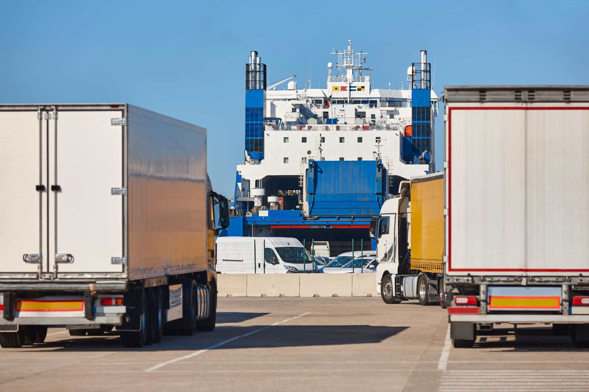 Cargo trucks lined up in front of a ro-ro vessel at a shipping port